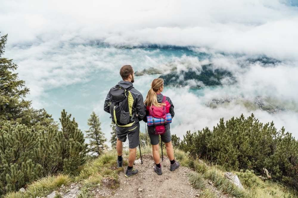 Young couple on a hiking trip in the mountains looking at view, Herzogstand, Bavaria, Germany